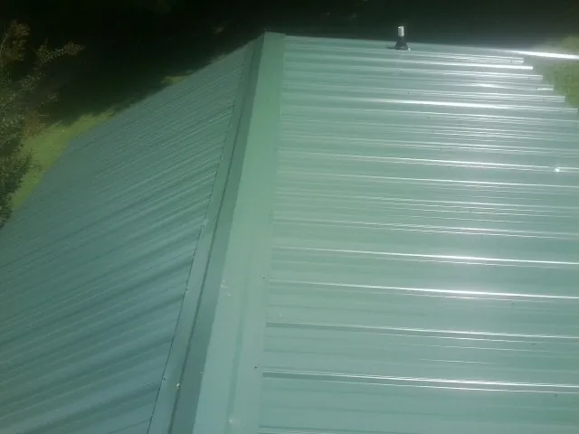 New green metal panels meeting at the ridge of a roof — Flat Roof Repair work by our crew in Cortez